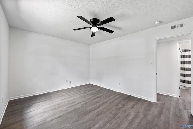 empty room featuring a textured ceiling, ceiling fan, visible vents, and dark wood-style floors