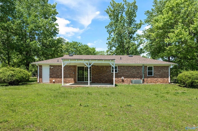 rear view of house with a lawn, a patio area, central air condition unit, and brick siding