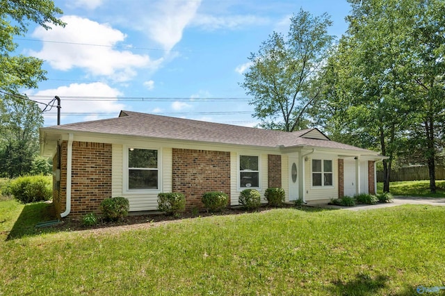 single story home with brick siding, a shingled roof, and a front yard