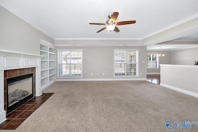 unfurnished living room with a tiled fireplace, built in features, crown molding, dark colored carpet, and baseboards