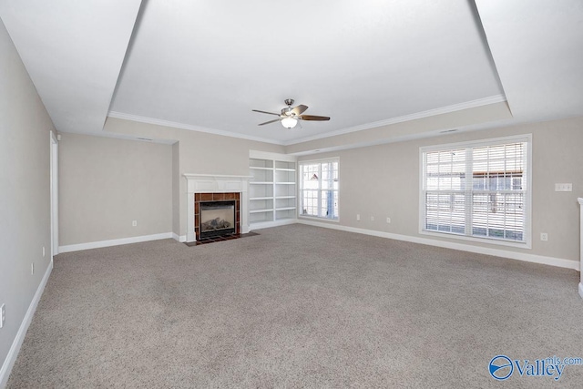 unfurnished living room featuring built in shelves, baseboards, a tile fireplace, ceiling fan, and carpet flooring