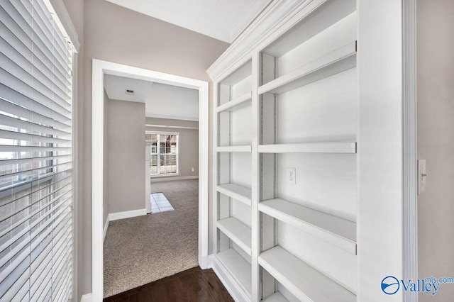 corridor featuring dark colored carpet, visible vents, and baseboards