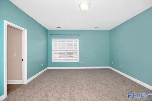 spare room with baseboards, carpet floors, and visible vents