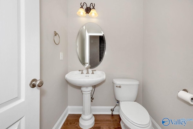 bathroom featuring toilet, wood finished floors, and baseboards