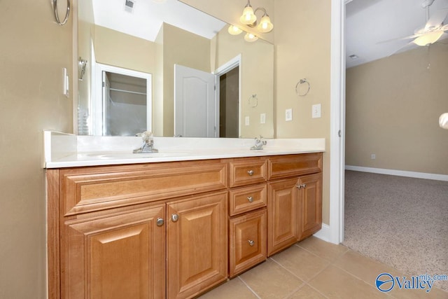 bathroom with a ceiling fan, a sink, tile patterned flooring, double vanity, and baseboards