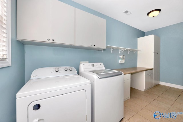 clothes washing area with visible vents, baseboards, light tile patterned flooring, cabinet space, and separate washer and dryer