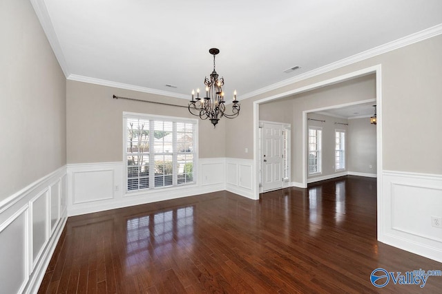 spare room featuring dark wood finished floors, a notable chandelier, visible vents, and a wainscoted wall