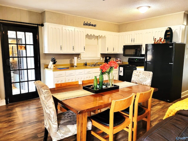 kitchen with black appliances, white cabinetry, dark wood finished floors, and a sink