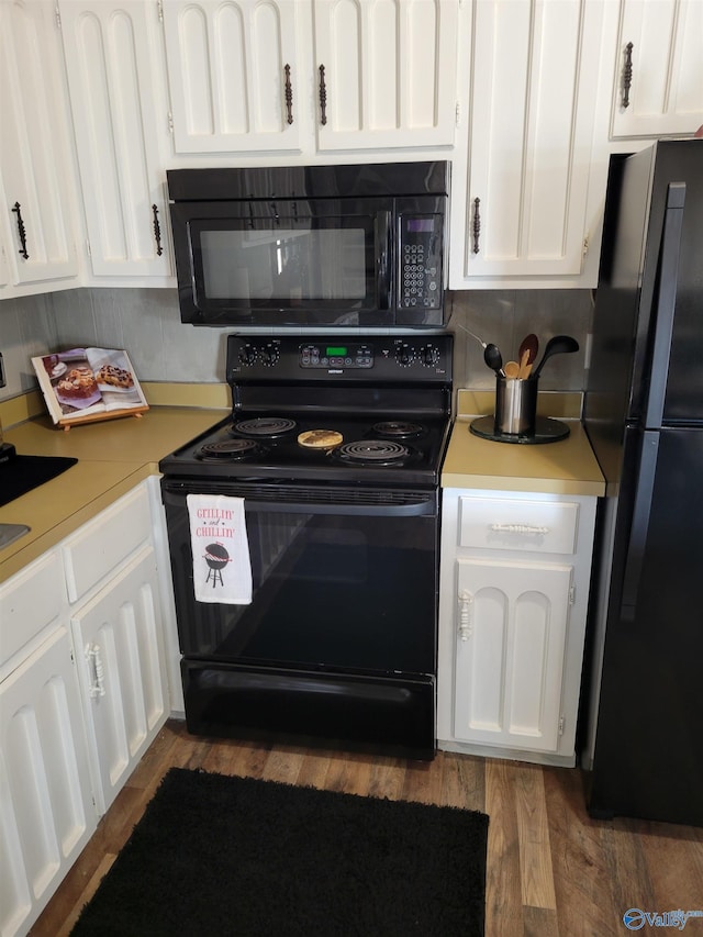 kitchen featuring black appliances, wood finished floors, light countertops, and white cabinetry