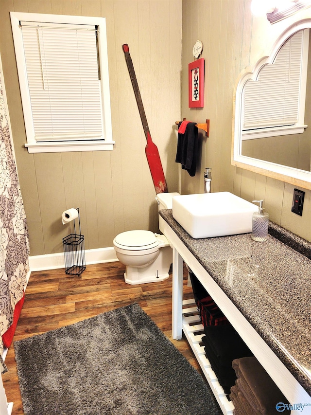 bathroom featuring toilet, baseboards, wood finished floors, and vanity