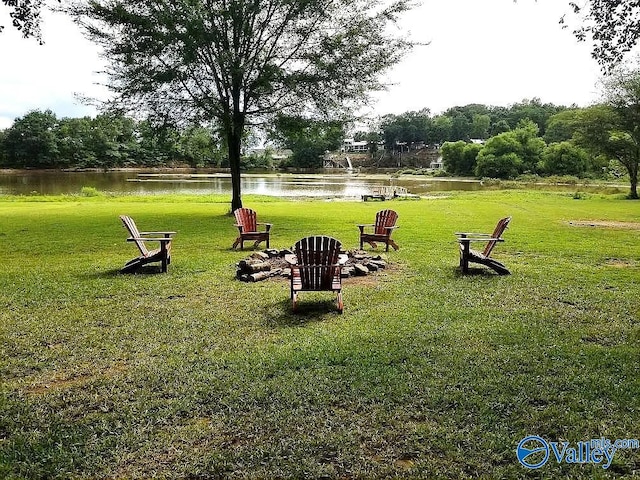 surrounding community with a water view and a lawn