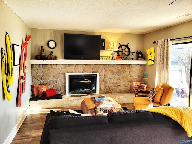 living area featuring a textured ceiling, a fireplace, baseboards, and wood finished floors