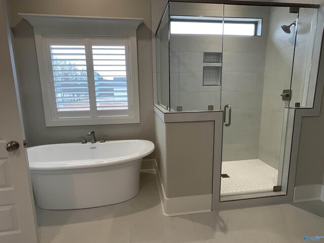 bathroom with a healthy amount of sunlight, independent shower and bath, and tile patterned flooring