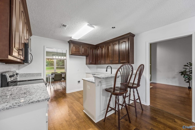 138 Spring Farm Rd, Huntsville, AL 35811 - kitchen featuring stainless steel appliances, a peninsula, dark brown cabinets, dark wood-type flooring, and a textured ceiling