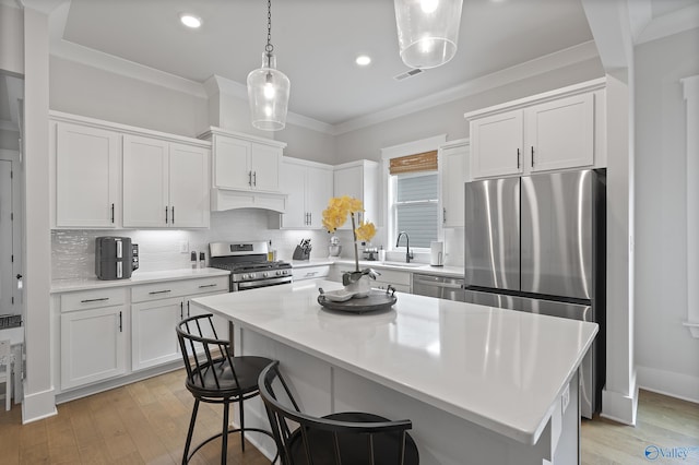 kitchen with white cabinetry, crown molding, stainless steel appliances, and a center island