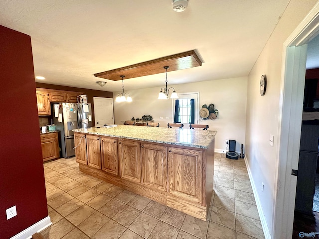 175 County Road 23, Leesburg, AL 35983 - kitchen with stainless steel refrigerator with ice dispenser, a kitchen island, light stone countertops, a chandelier, and baseboards