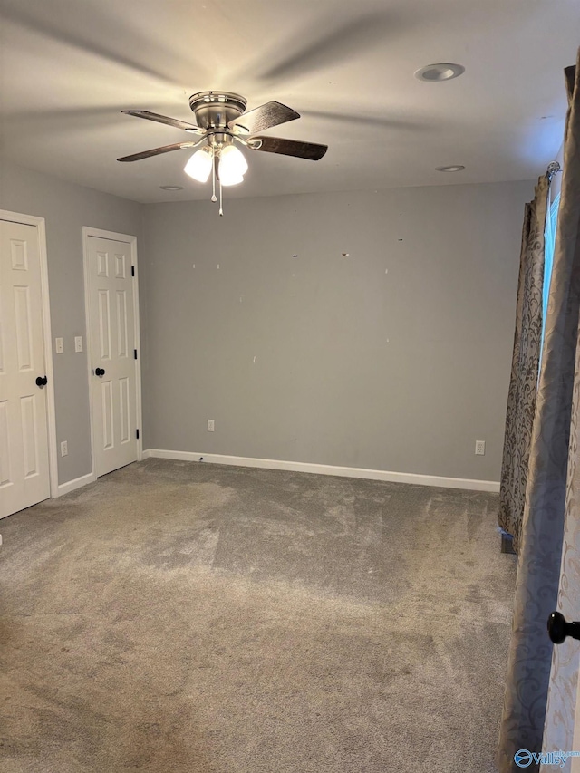 carpeted empty room with baseboards and a ceiling fan