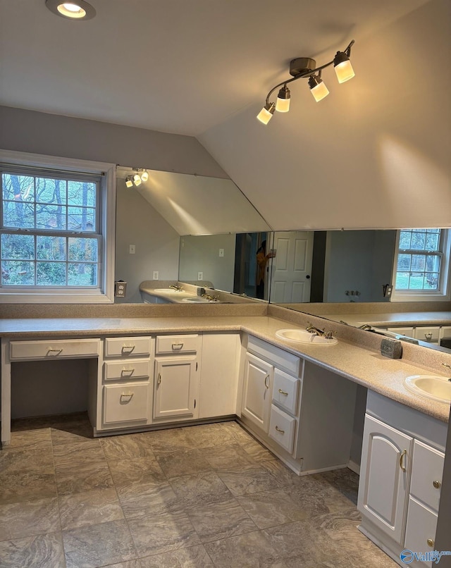 bathroom featuring vaulted ceiling, double vanity, and a sink