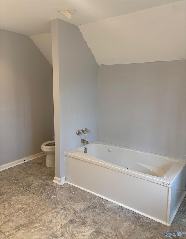 full bathroom featuring baseboards, vaulted ceiling, toilet, and a bath