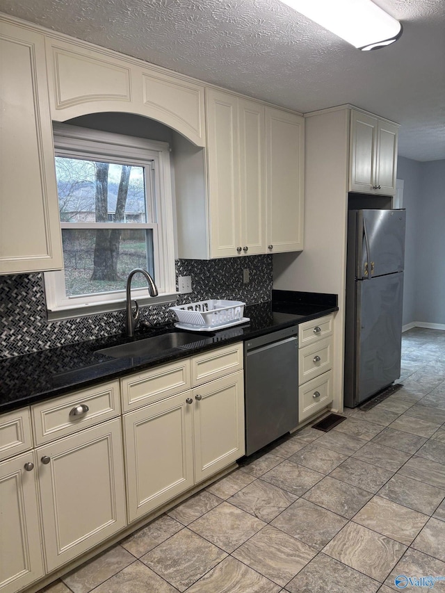 kitchen featuring dark countertops, tasteful backsplash, appliances with stainless steel finishes, and a sink