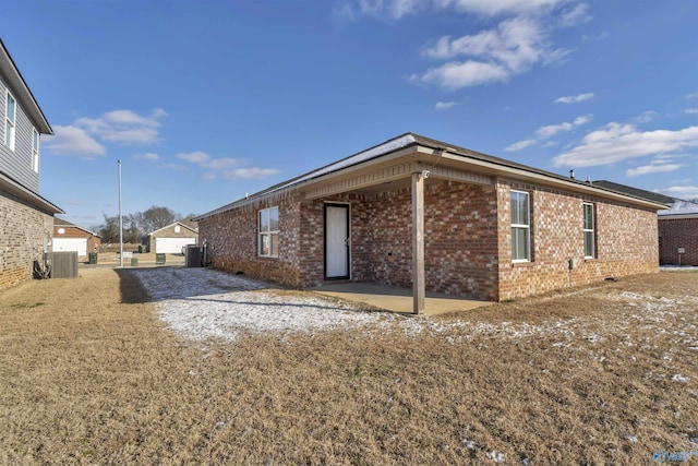 view of property exterior with brick siding, cooling unit, and a patio