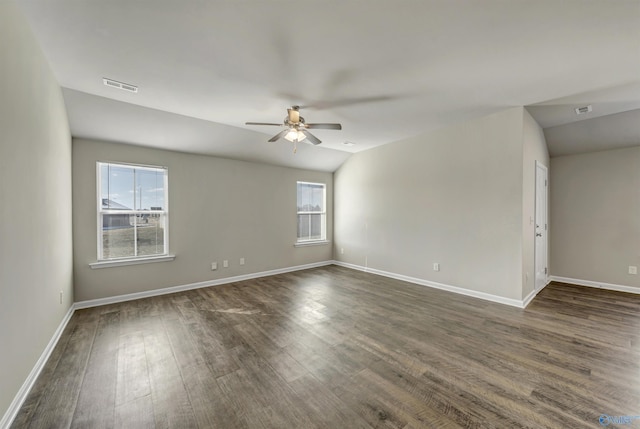 spare room with dark wood-style floors, visible vents, baseboards, and a ceiling fan