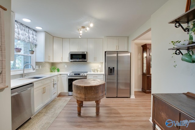 kitchen with white cabinets, appliances with stainless steel finishes, sink, and light wood-type flooring