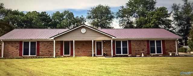 view of front of property featuring a front lawn, brick siding, and metal roof