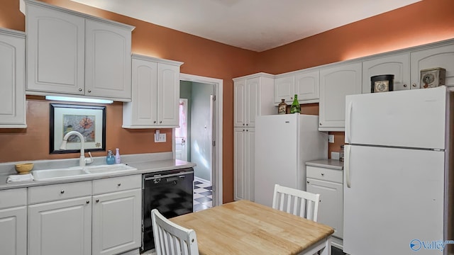 kitchen with black dishwasher, a sink, freestanding refrigerator, and white cabinetry