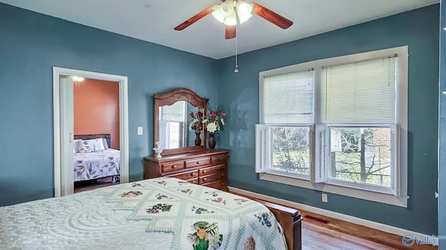 bedroom featuring a ceiling fan, baseboards, and wood finished floors