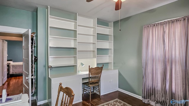 office area with ceiling fan, built in desk, dark wood-style flooring, and baseboards