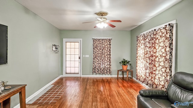 sitting room with wood-type flooring, baseboards, and ceiling fan