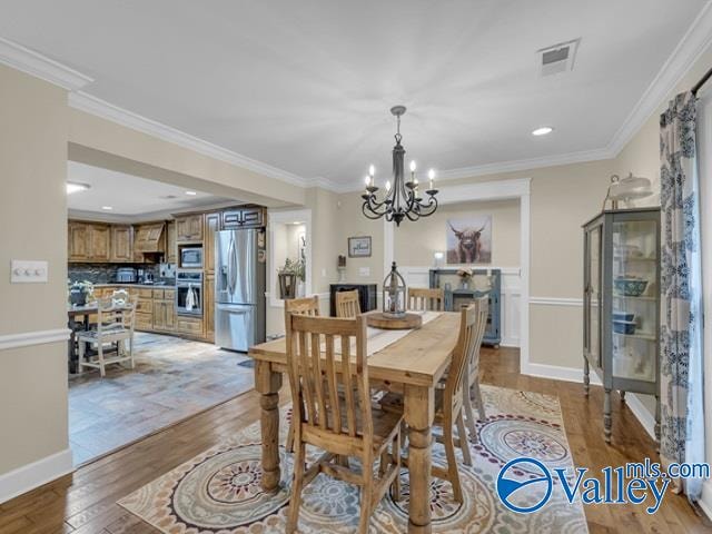 dining space with light hardwood / wood-style floors, a notable chandelier, and ornamental molding