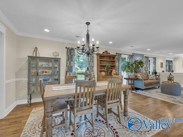 dining room featuring wood-type flooring, ornamental molding, and a chandelier