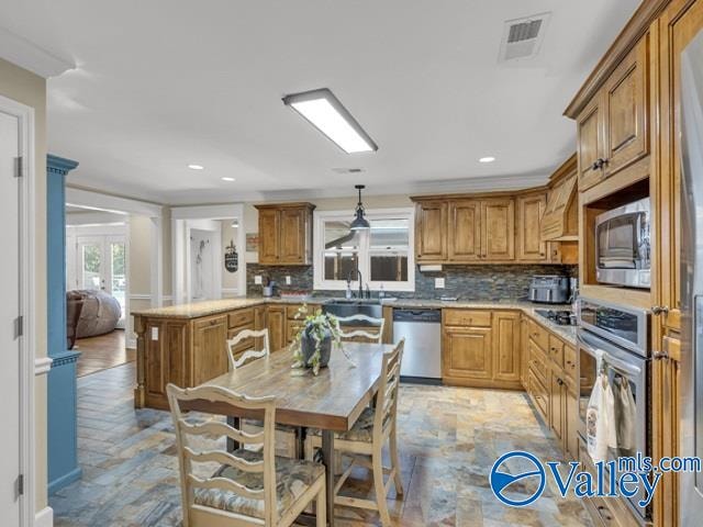 kitchen featuring appliances with stainless steel finishes, sink, backsplash, decorative columns, and pendant lighting