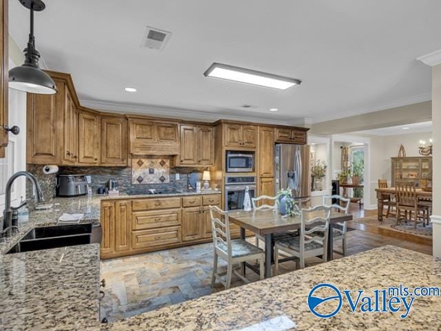 kitchen with light stone countertops, sink, stainless steel appliances, decorative light fixtures, and decorative backsplash