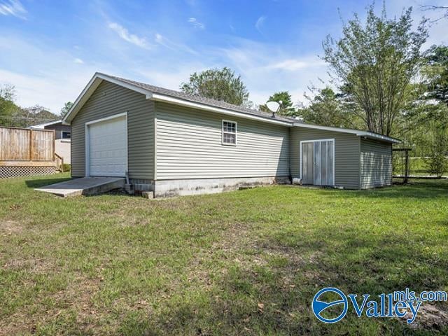 back of house featuring a yard, an outbuilding, and a garage