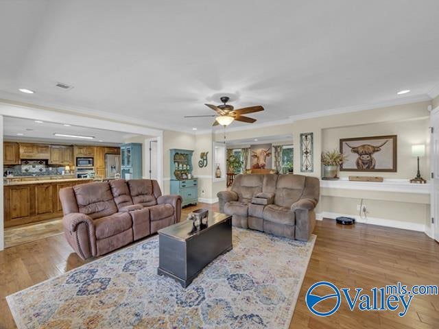 living room with hardwood / wood-style floors, crown molding, and ceiling fan