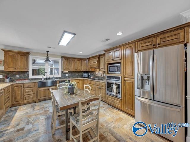 kitchen with tasteful backsplash, sink, stainless steel appliances, pendant lighting, and custom range hood