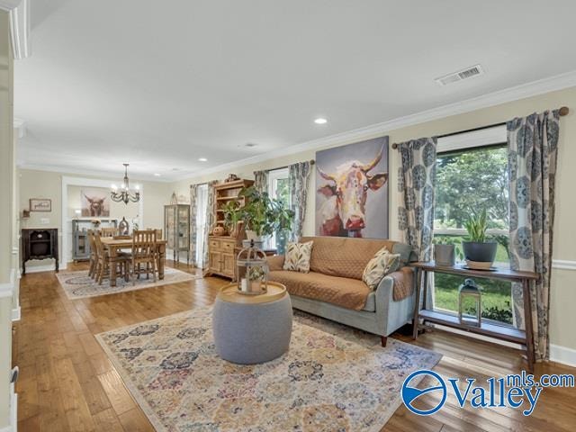 living room with light hardwood / wood-style flooring, a healthy amount of sunlight, a chandelier, and crown molding