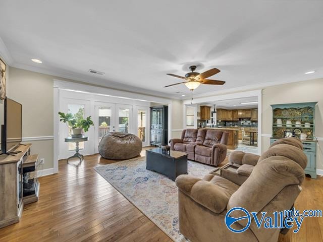 living room with french doors, wood-type flooring, crown molding, and ceiling fan