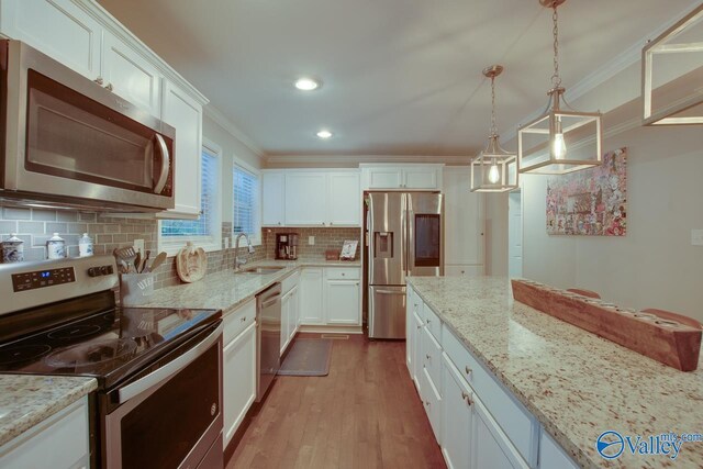 kitchen featuring appliances with stainless steel finishes, decorative light fixtures, white cabinetry, sink, and decorative backsplash