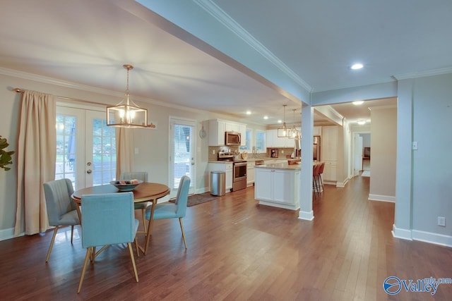 dining space featuring a notable chandelier, crown molding, french doors, and hardwood / wood-style flooring