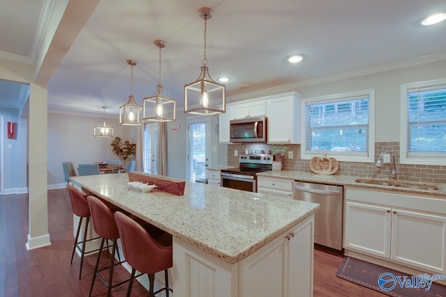 kitchen with pendant lighting, white cabinetry, sink, a center island, and stainless steel appliances