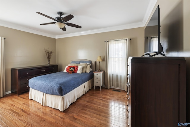 bedroom with visible vents, wood-type flooring, a ceiling fan, and crown molding