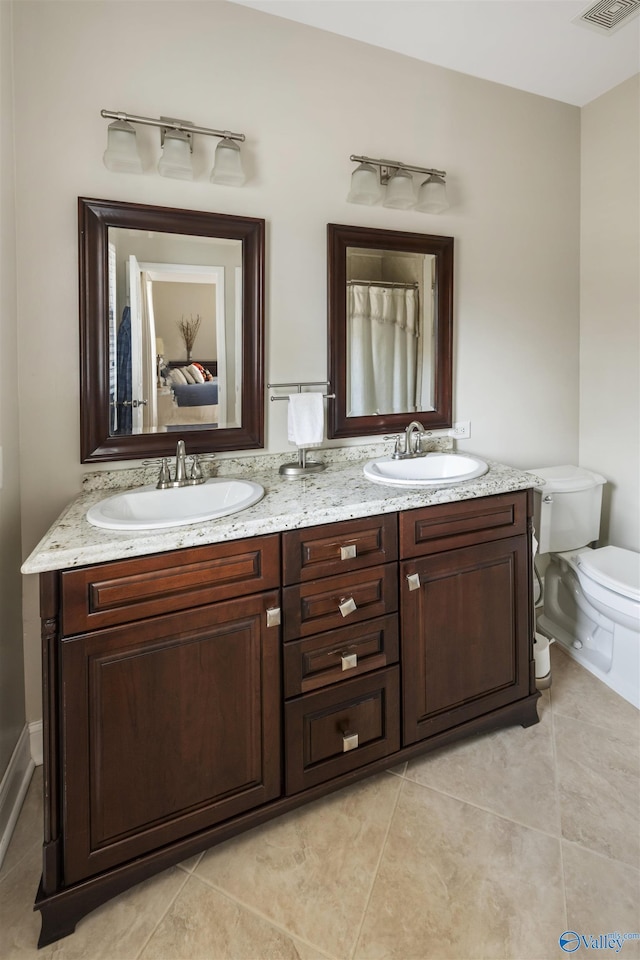 bathroom featuring double vanity, toilet, tile patterned floors, and a sink