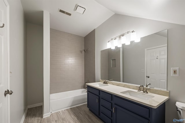 full bathroom with vaulted ceiling, visible vents, wood finished floors, and a sink