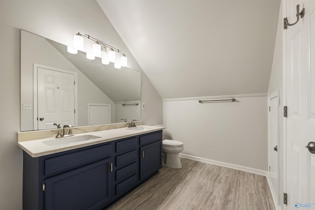 bathroom with vaulted ceiling, wood finished floors, and a sink