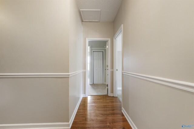 hallway featuring a textured ceiling, baseboards, and wood finished floors