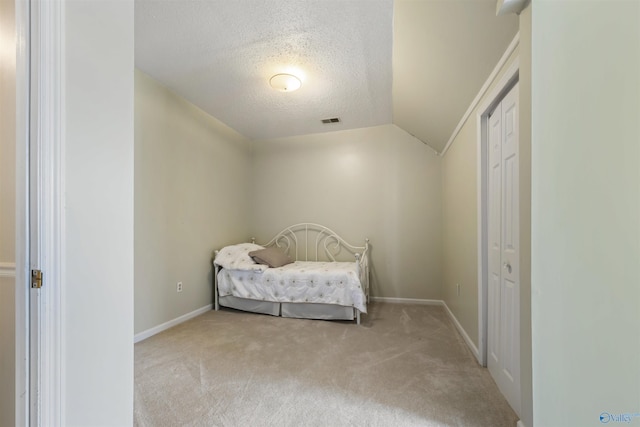 carpeted bedroom with visible vents, a textured ceiling, baseboards, and vaulted ceiling